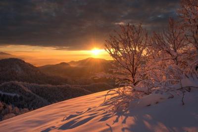winter sun rising over snowy mountains