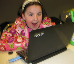Photo of a child at her computer, looking very excited